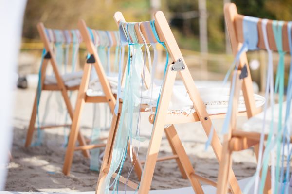 Stühle mit blauen Bändern für eine Hochzeit am Strand